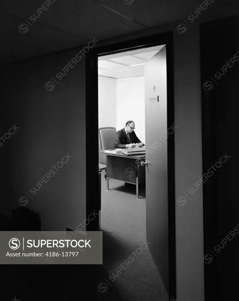 1960S 1970S Executive Businessman At Desk Seen Working Late Through Door Ajar 