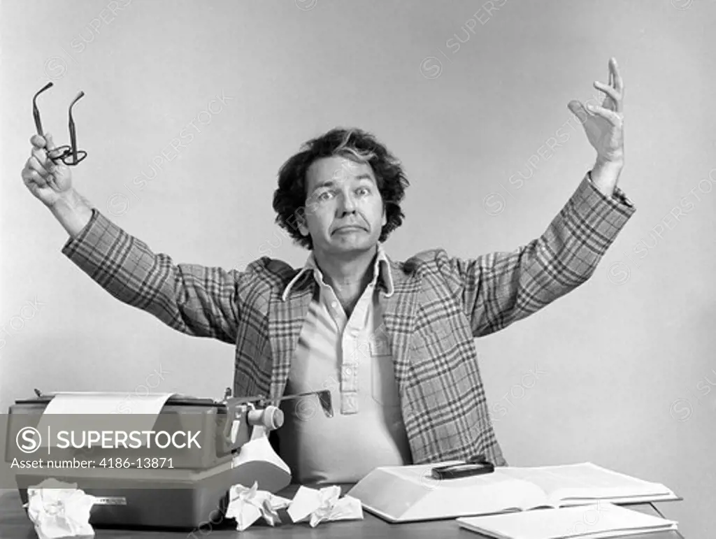 1970S Man At Desk Typewriter Crumpled Papers Arms Up In Air Exasperated Expression Indoor