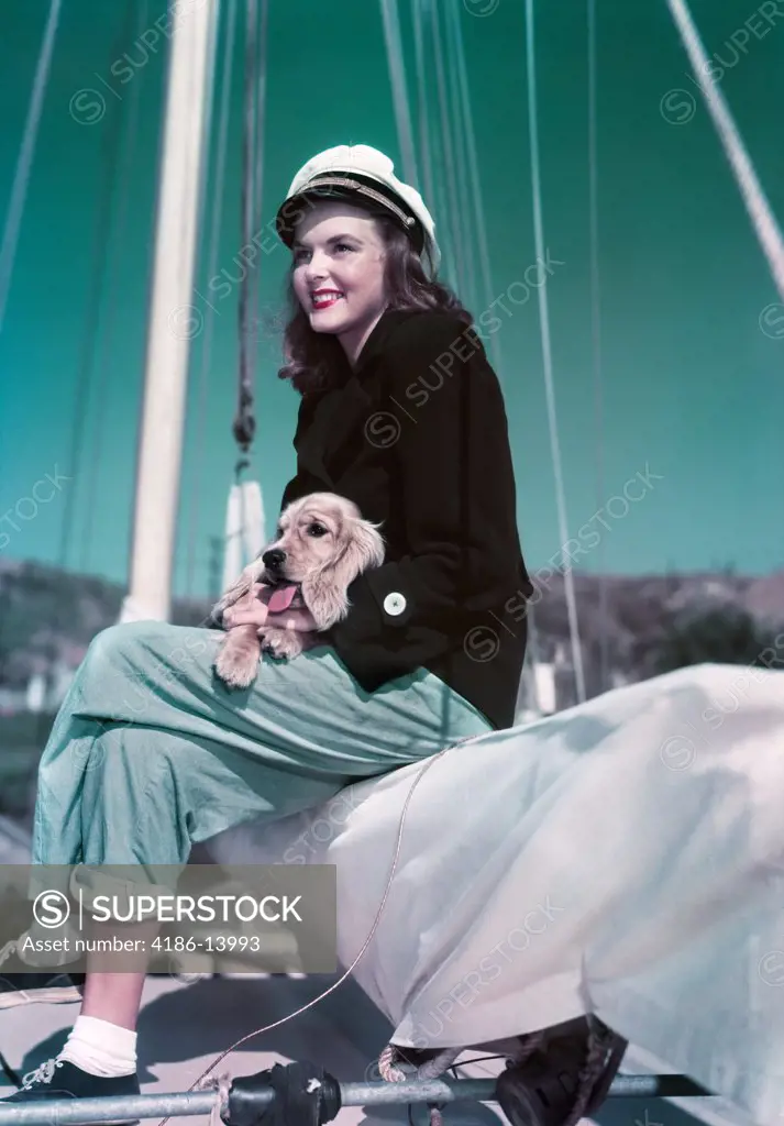 1940S 1950S Smiling Woman Wearing Sailing Yachting Outfit Sitting On Edge Of Sailboat Holding Puppy In Lap