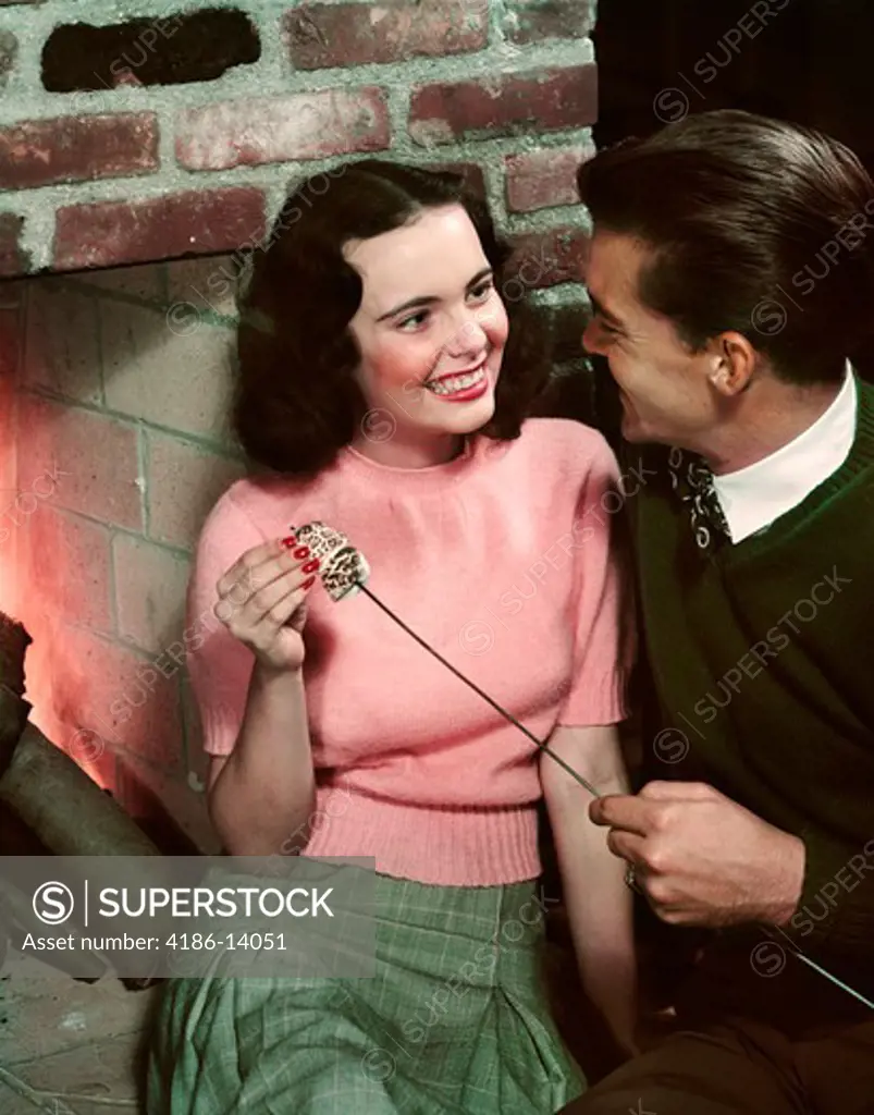 1950S Smiling Teen Couple Toasting Marshmallows In Fireplace