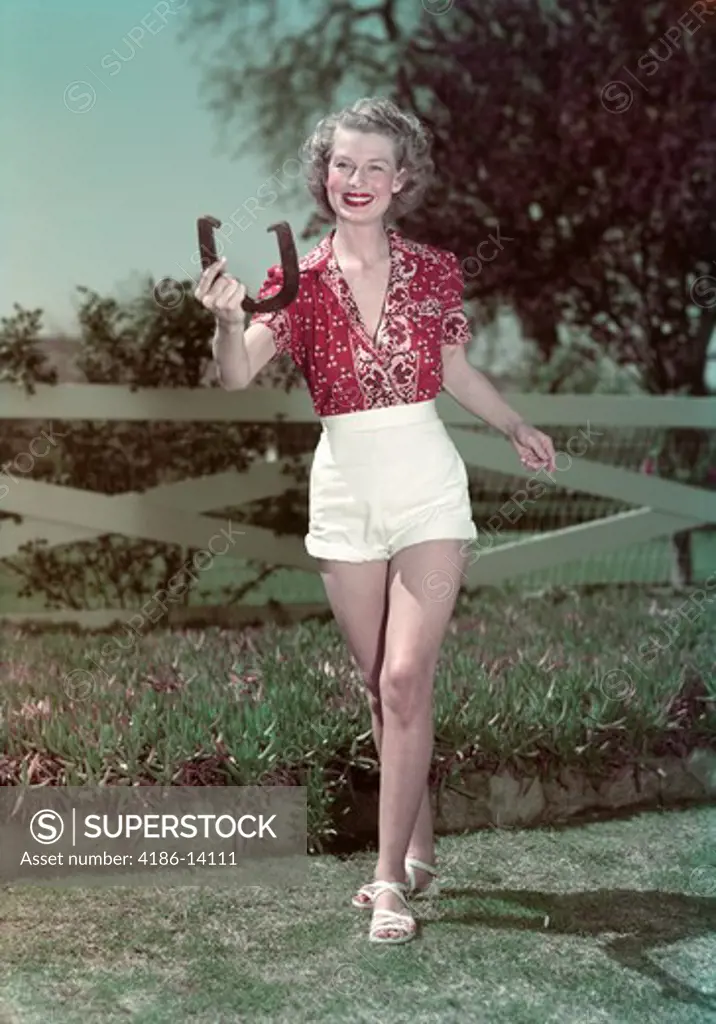1940S 1950S Smiling Woman Tossing Horseshoe Fence In Background
