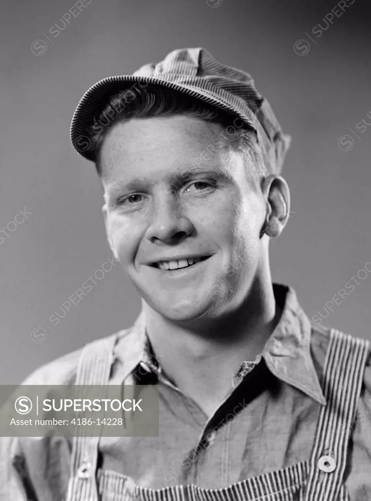 1940S Portrait Of Smiling Blue Collar Working Man Wearing Overhauls And Engineer Hat Studio