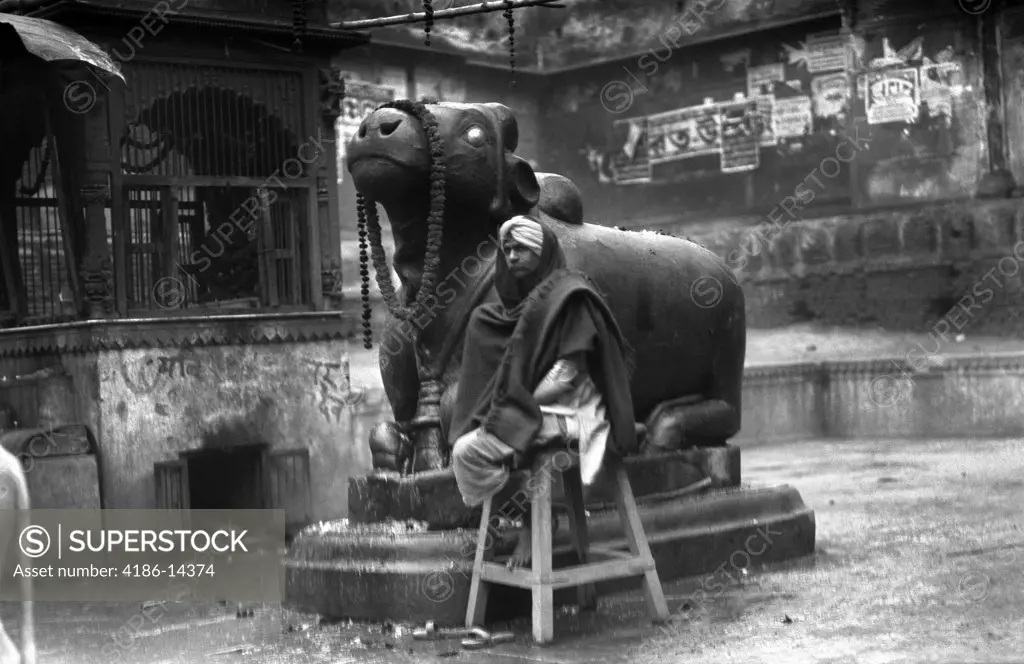 1920S 1930S Benares India Man In Turban Seated By Statue Of Nandi Scared Hindu God Bull Religion Hinduism