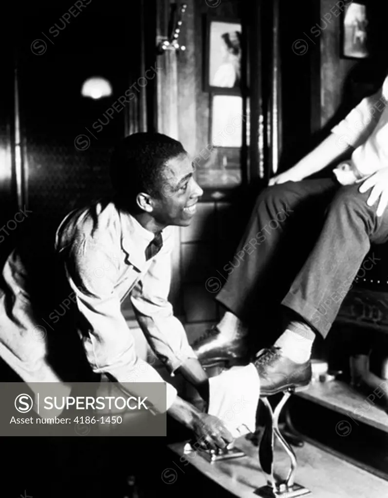 1930S African American Man Smiling Shining Shoes On Seated Patron At Shoeshine Stand