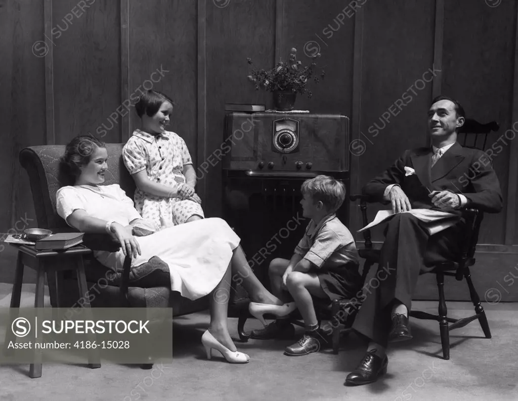 1930S Family Man Father Woman Mother Girl Daughter Boy Son In Living Room Gathered Around Listening To Radio