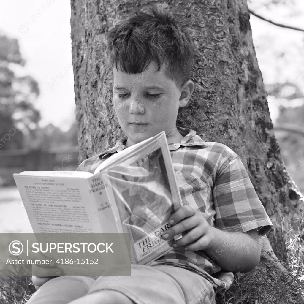 1960S 1970S Boy Leaning Against Tree Reading Book