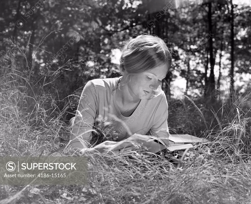 1970S Woman Lying Stomach-Down In Field Reading Book