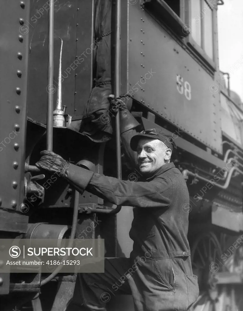 1930S Railroad Worker In Coveralls Hat Goggles & Gloves Climbing Up Onto Train
