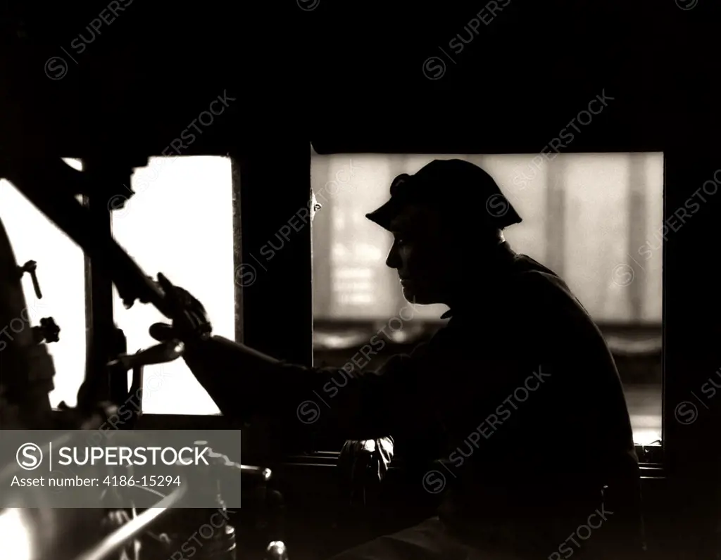 1920S 1930S 1940S Silhouette Train Engineer At Controls In Locomotive Cab Of Railroad Steam Engine