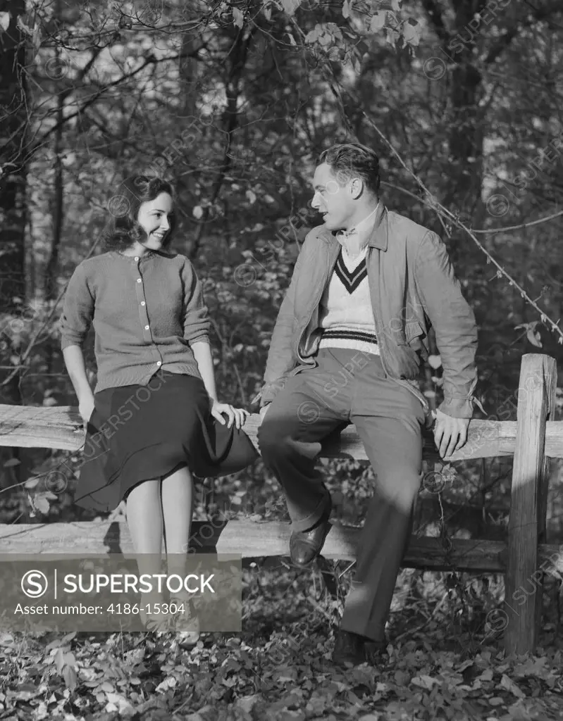 1940S Young Couple Sitting On Fence Autumn Smiling At One Another