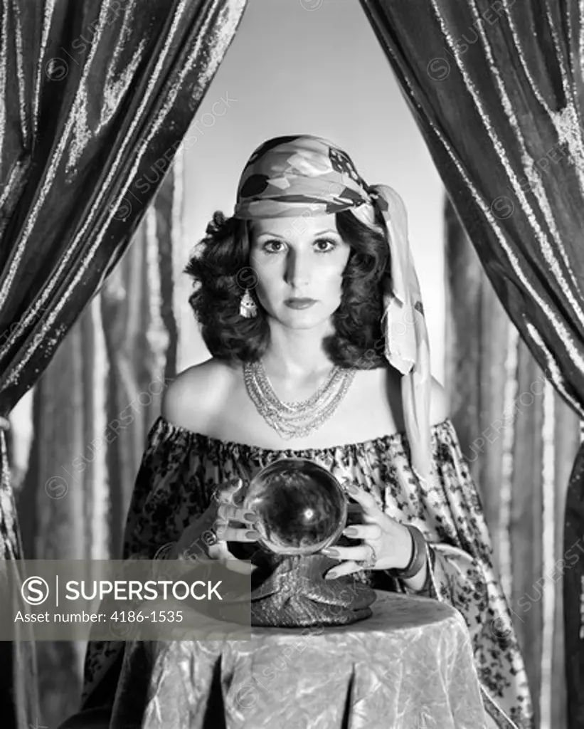 1970S Gypsy Woman Between Sparkly Curtains With Hands Around Crystal Ball Staring Into Camera
