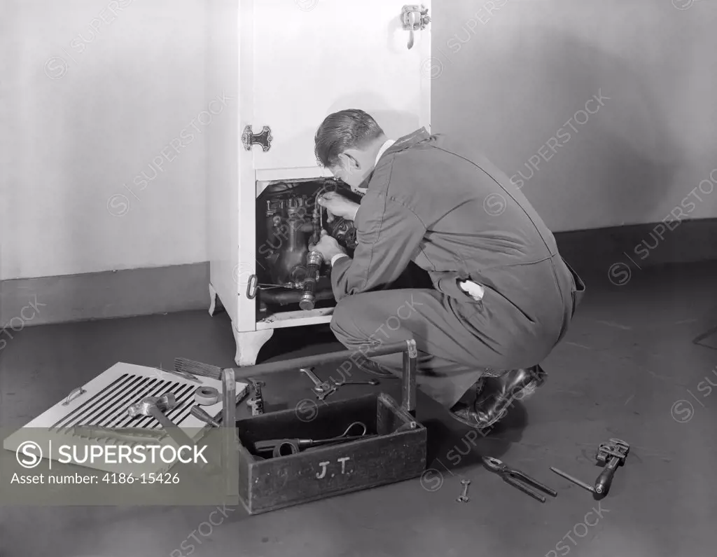 1930S 1940S Man Workman Fixing Refrigeration Machinery Of Refrigerator In Kitchen Repair Service
