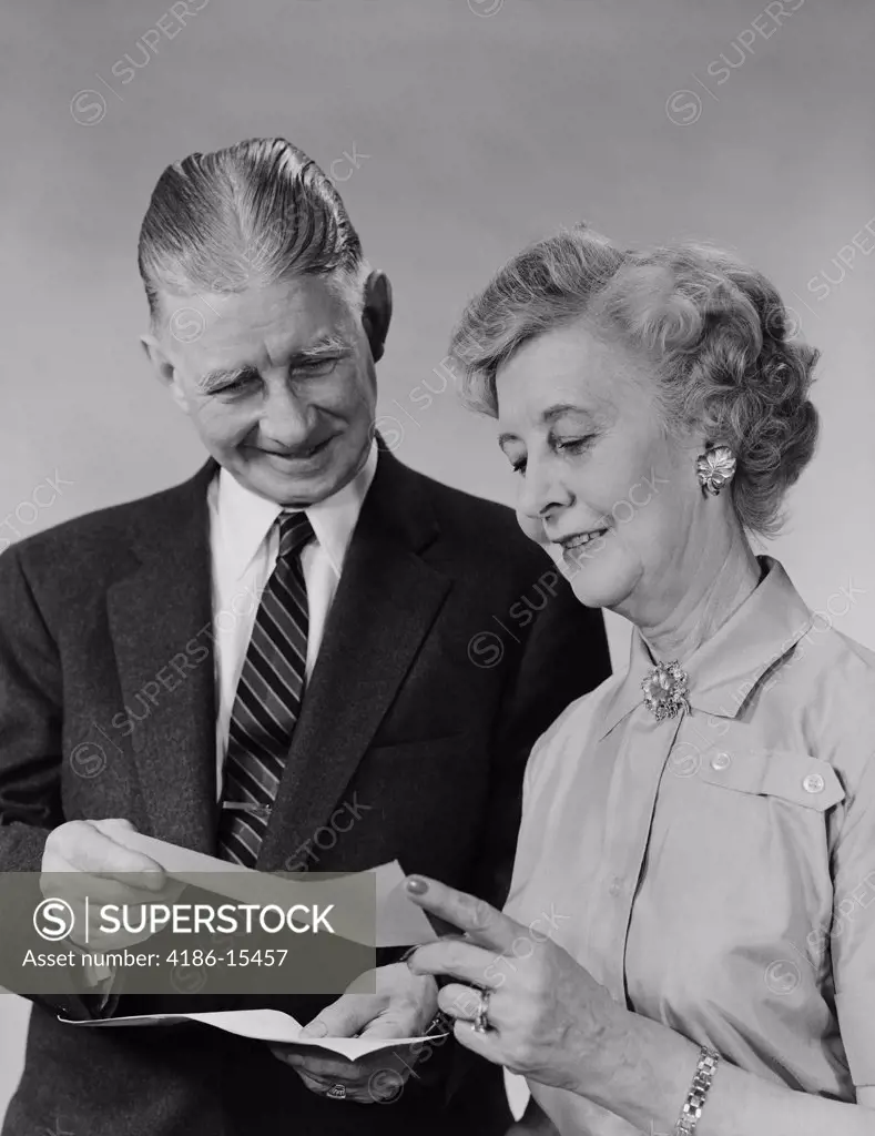 1960S Senior Couple Man Woman Reading Holding Check