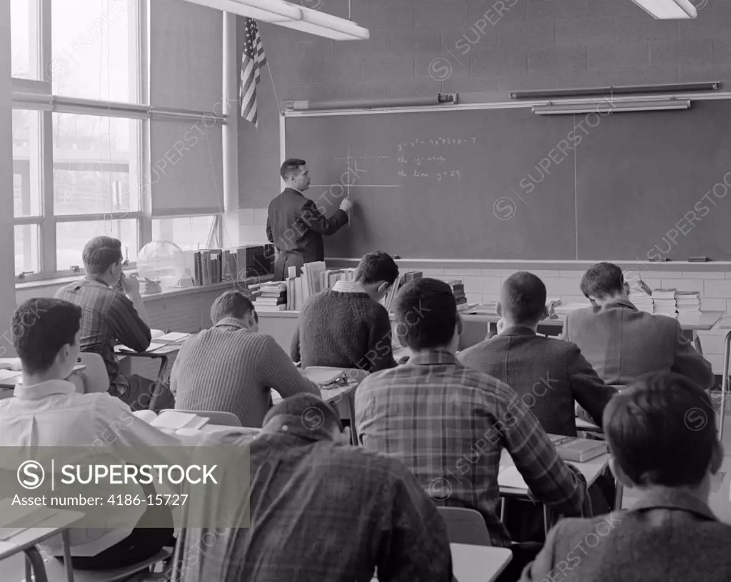 1960S Angled Back View Of Classroom With Teacher At Blackboard Plotting Complex Equation In Graph Form