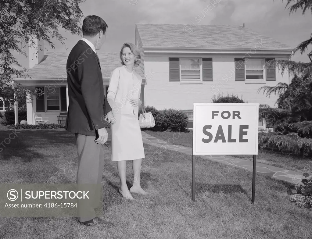1960S Couple Man Woman Standing In Front Of House With For Sale Sign In Yard