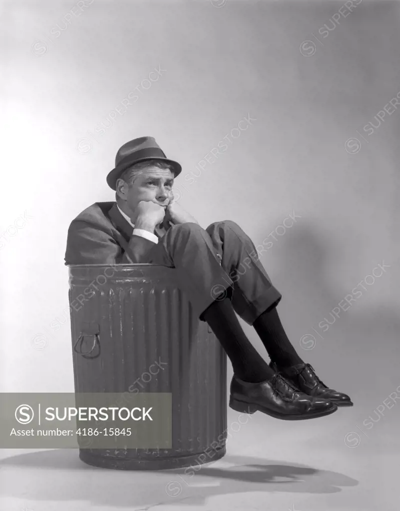 1960S Businessman In Suit And Hat Sitting In Trashcan