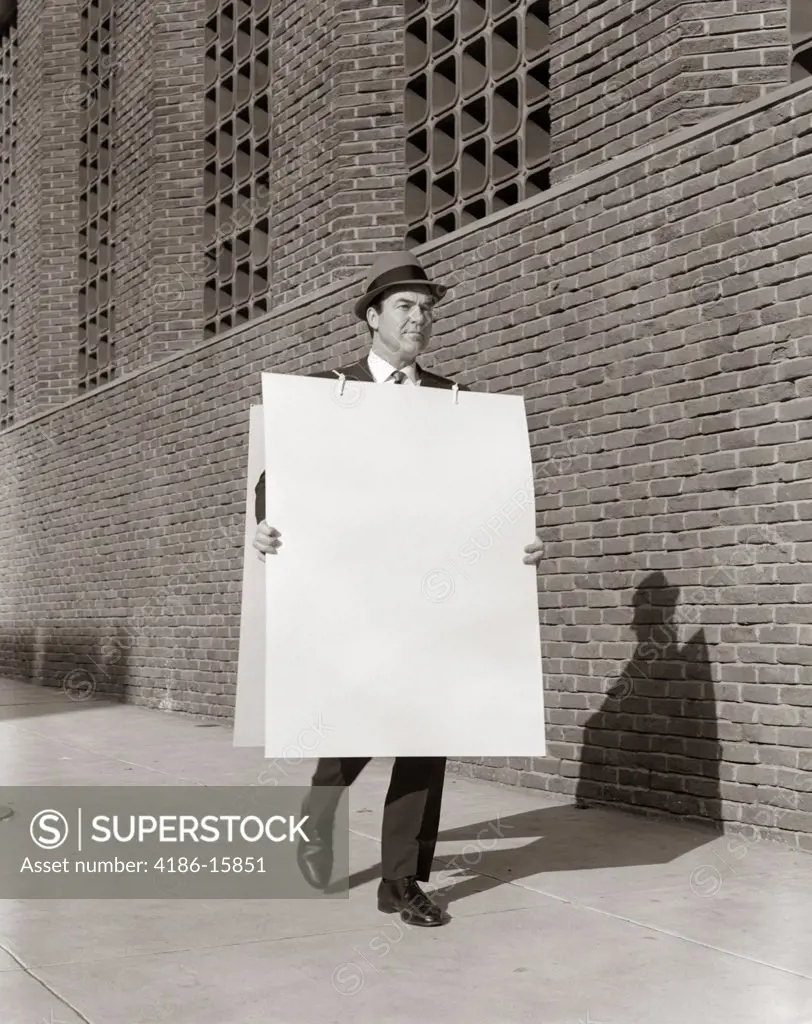 Businessman Or Salesman In Hat Walking Sidewalk Wearing Advertising Sandwich Board Symbolic Of Communication Outdoor