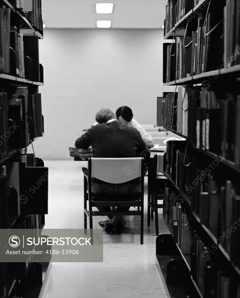 1970S Pair Of Male College Students Studying In Library Framed By Bookshelves