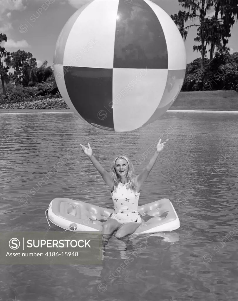 1960S Young Woman On Inflatable Raft In Pool Catching Large Beach Ball Summer Outdoor