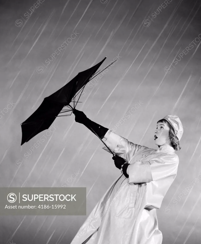 1950S Woman In Rain Coat Trying To Use Broken Umbrella To Keep Dry