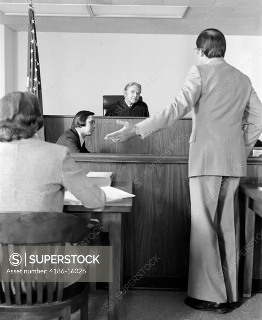 1970S Lawyer Pointing To Plaintiff Pleading Case Before Court Room Judge  