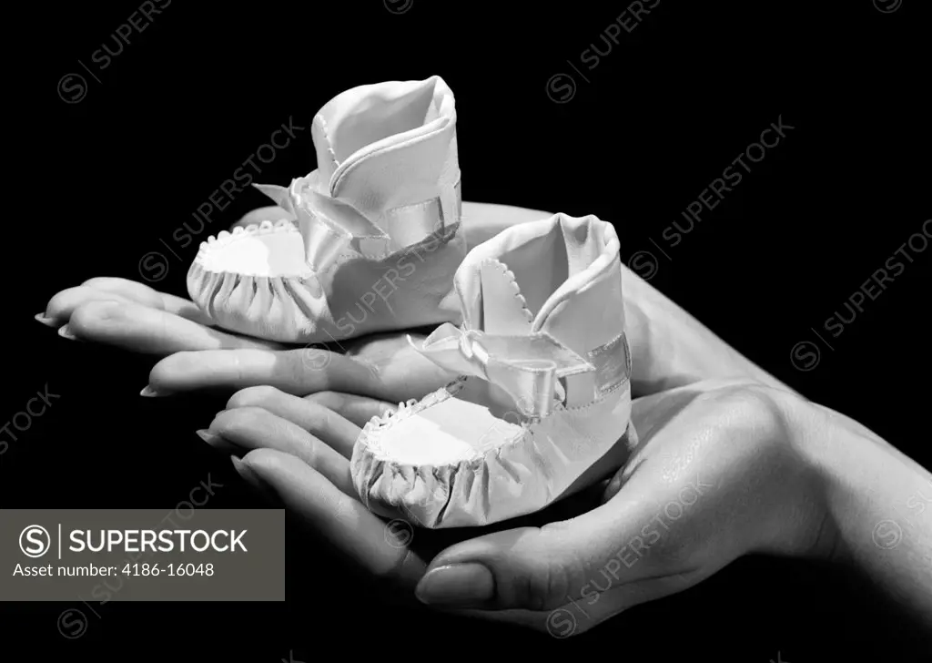 1950S Woman Mother Holding One Baby Bootie Shoe In Each Hand