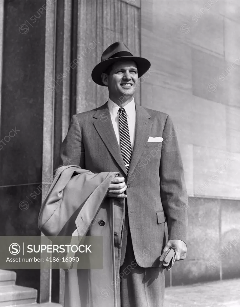 1950S Young Man In Suit And Striped Tie Wearing Hat Holding Coat Over His Arm Gloves Businessman Portrait Fashion
