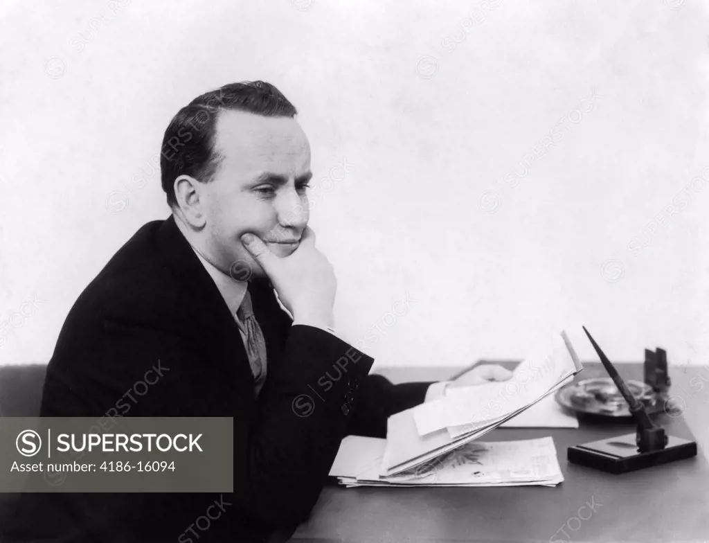 1930S Man Sitting At Desk Holding Papers With Concerned Look On Face
