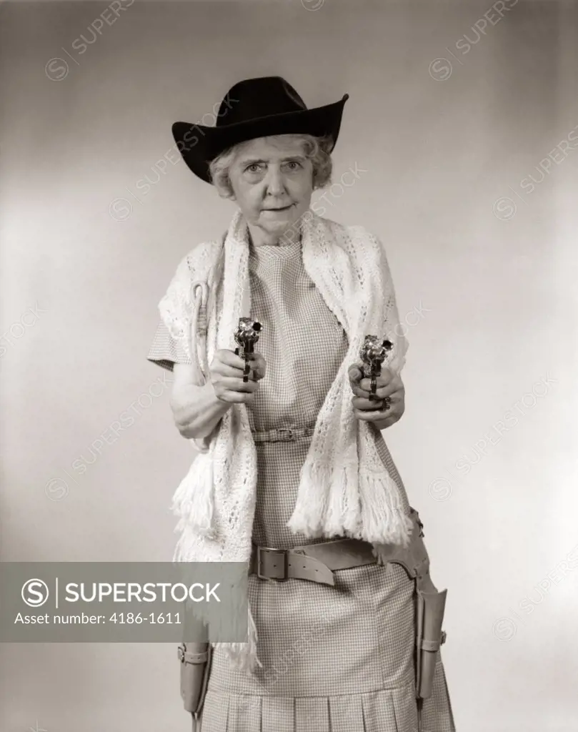 1950S Granny Cowgirl Wearing Hat & Shawl & Pointing 2 Pistols At Camera