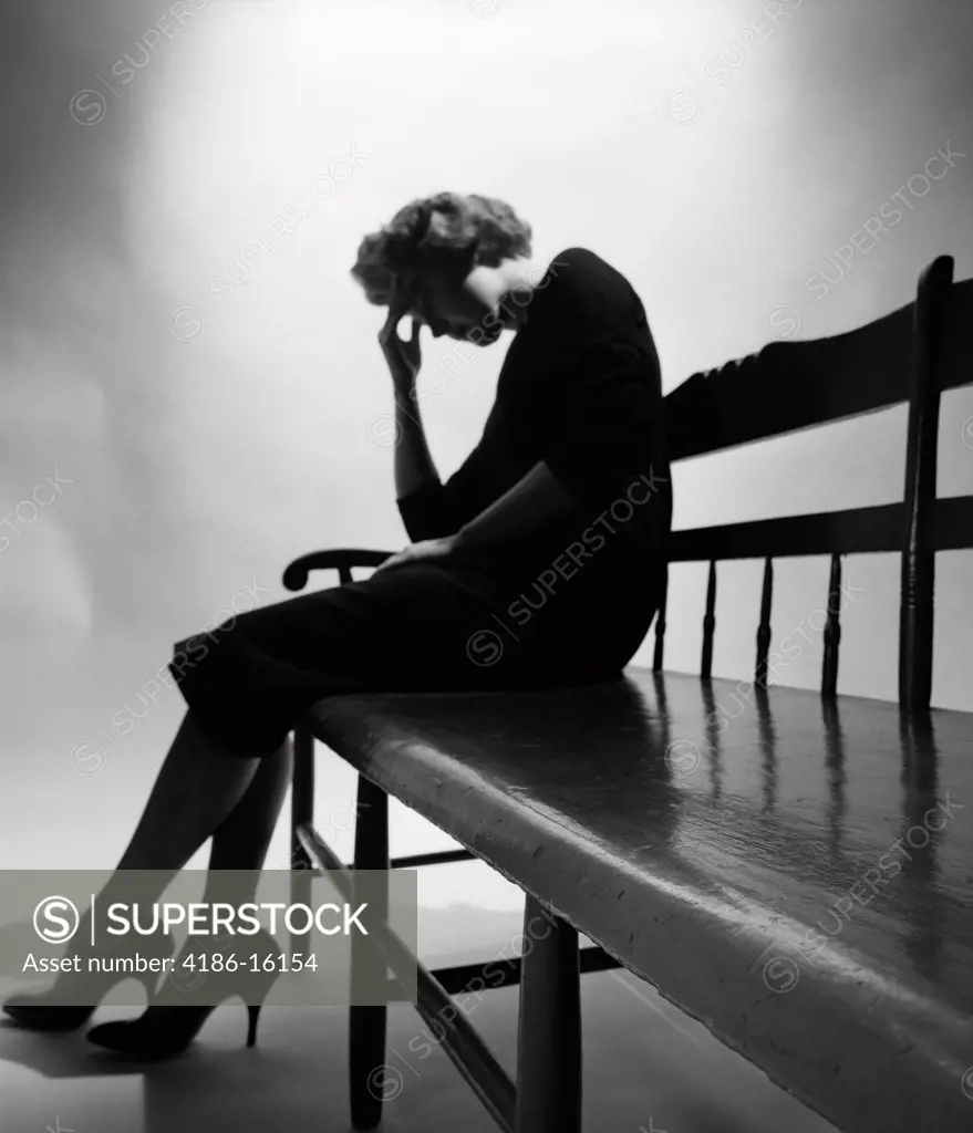 1950S Woman In Silhouette Sitting At End Of Bench Holding Forehead In Hand