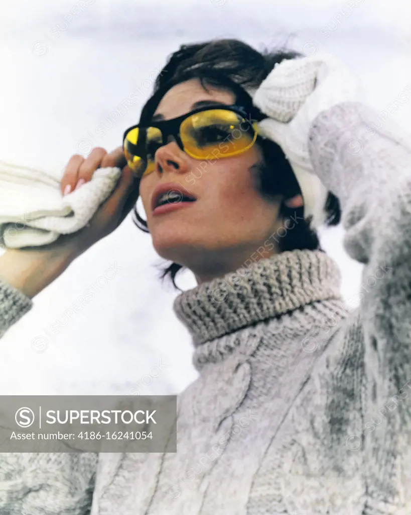 1970s BRUNETTE WOMAN IN CABLE KNIT TURTLENECK SWEATER LIFTING SKI GOGGLES SUNGLASSES WINTER PORTRAIT
