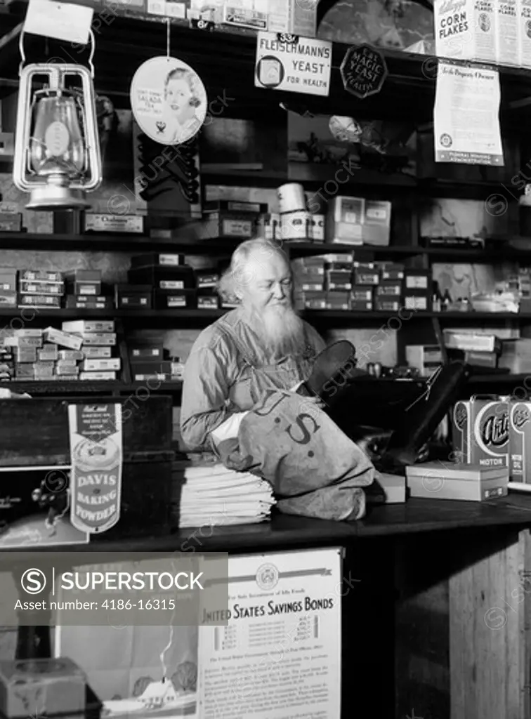 1930S Bearded Grocer Behind Counter In General Store Looking At Rubber Boots