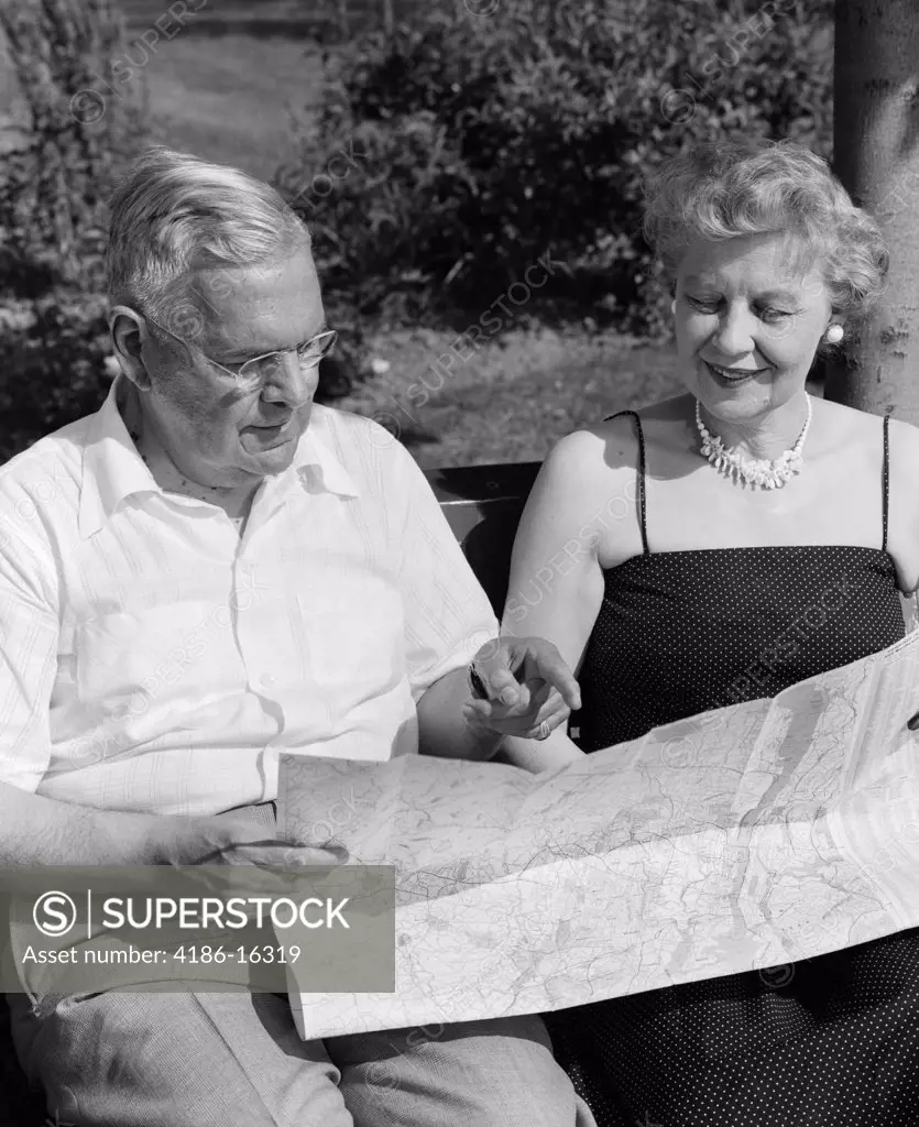 1950S Elderly Couple Seated On Bench Looking At Map