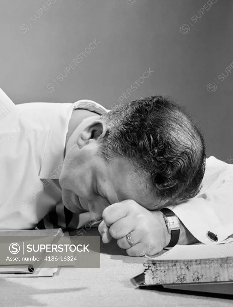 1950S Man With Head On Desk In Frustration Exhaustion