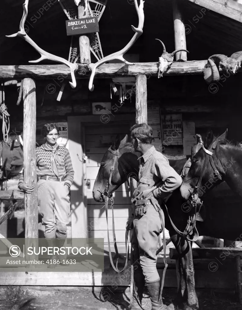 1920S 1930S Couple And Horses In Front Of Western Hunting Lodge Porch With Trophy Antlers Skulls Brazeau Lake Alberta