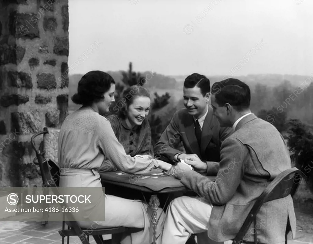 1930S Two Couples Men Women Play Playing Cards At Table On Outdoor Patio Social Card Game Bridge Retro Vintage Lifestyle Upscale