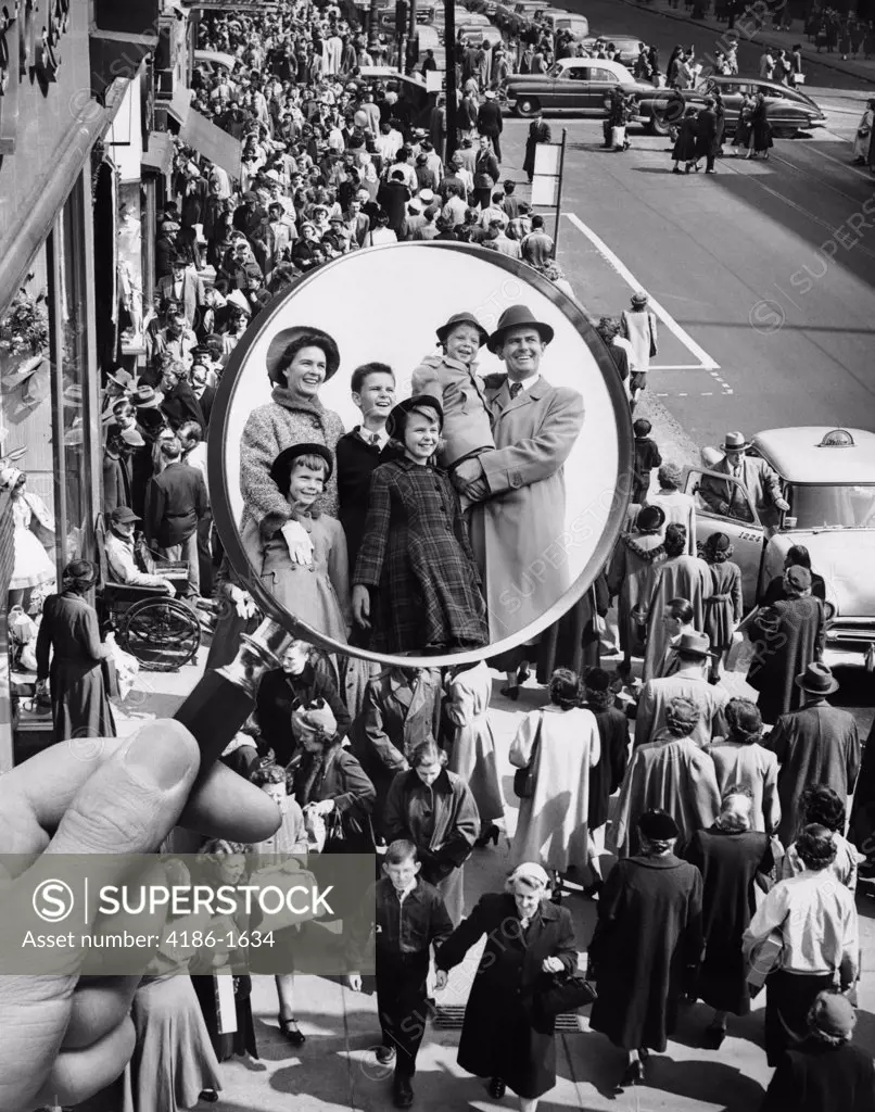 1950S Montage Of Family In Magnifying Glass Superimposed Over Crowded Sidewalk