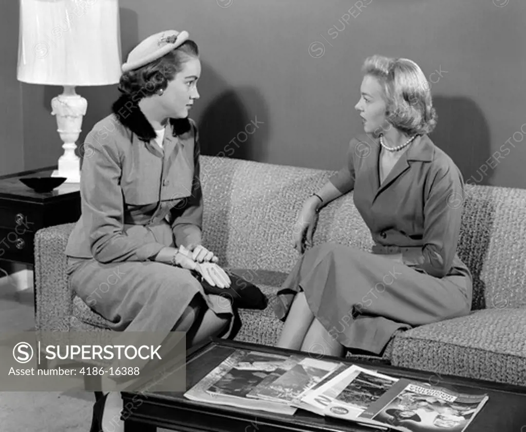 1950S Pair Of Women Sitting On Living Room Sofa Talking One Wearing Suit With Hat & Gloves