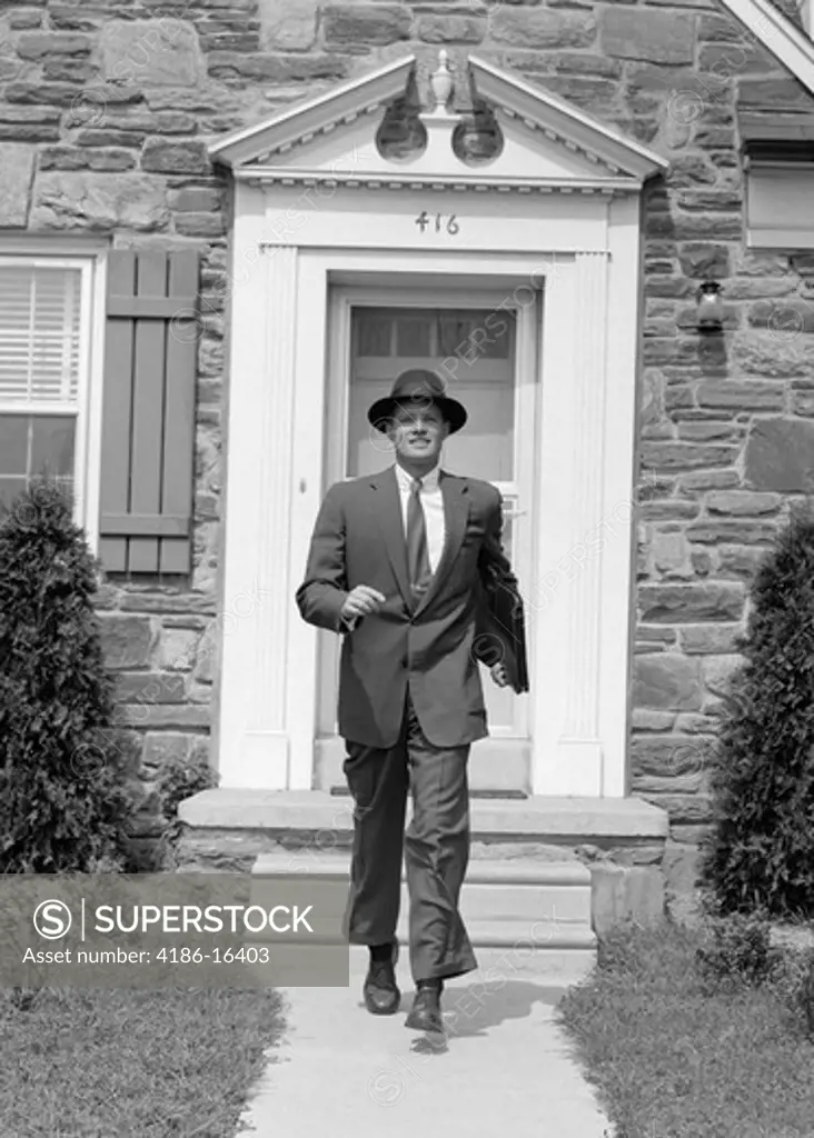1950S Man Smiling Businessman Proud Look Of Satisfaction Walking Out Suburban House Front Door Wearing Hat Carrying Briefcase