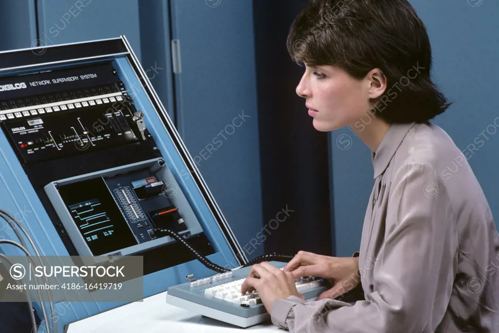 1980s BRUNETTE WOMAN MONITORING A NETWORK CONTROLLER 