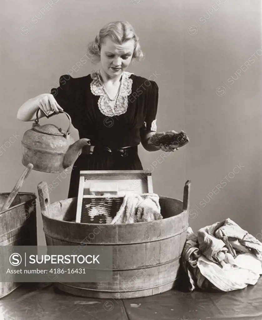 1940S Displeased Housewife Pouring Water From Kettle Into Bucket With Washboard & Towel