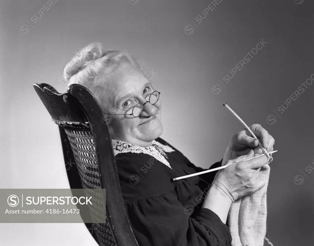 1950S 1960S Senior Elderly Woman Knitting Smiling Turning To Look At Camera Granny Glasses