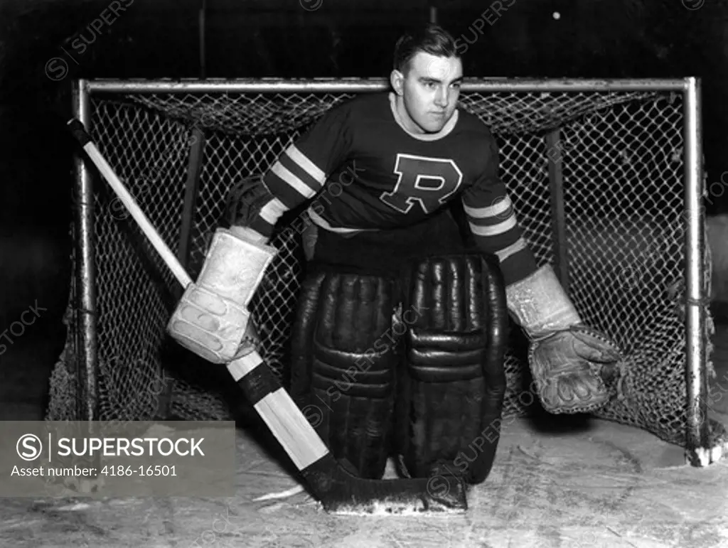 1940S Serious Ice Hockey Goalie Standing In Front Of The Net With Gloves Padding Jersey And Puck