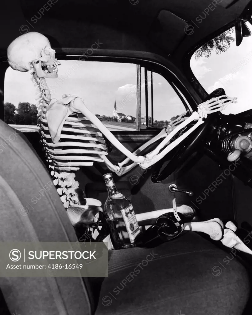 1930S 1940S Still Life Of Skeleton Driving Car With Whiskey Bottle And Woman'S Shoes On Seat Beside It