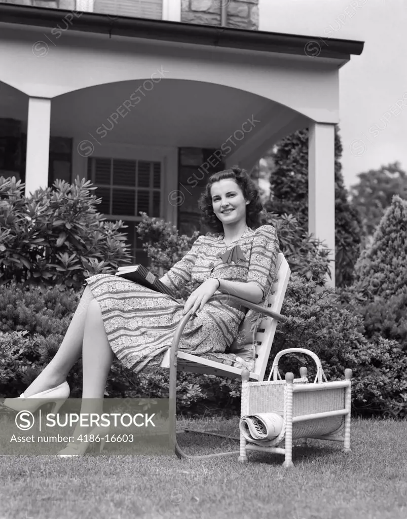 1940S Woman Holding Book Smiling At Camera Sitting In Lawn Chair Magazine Rack Porch House