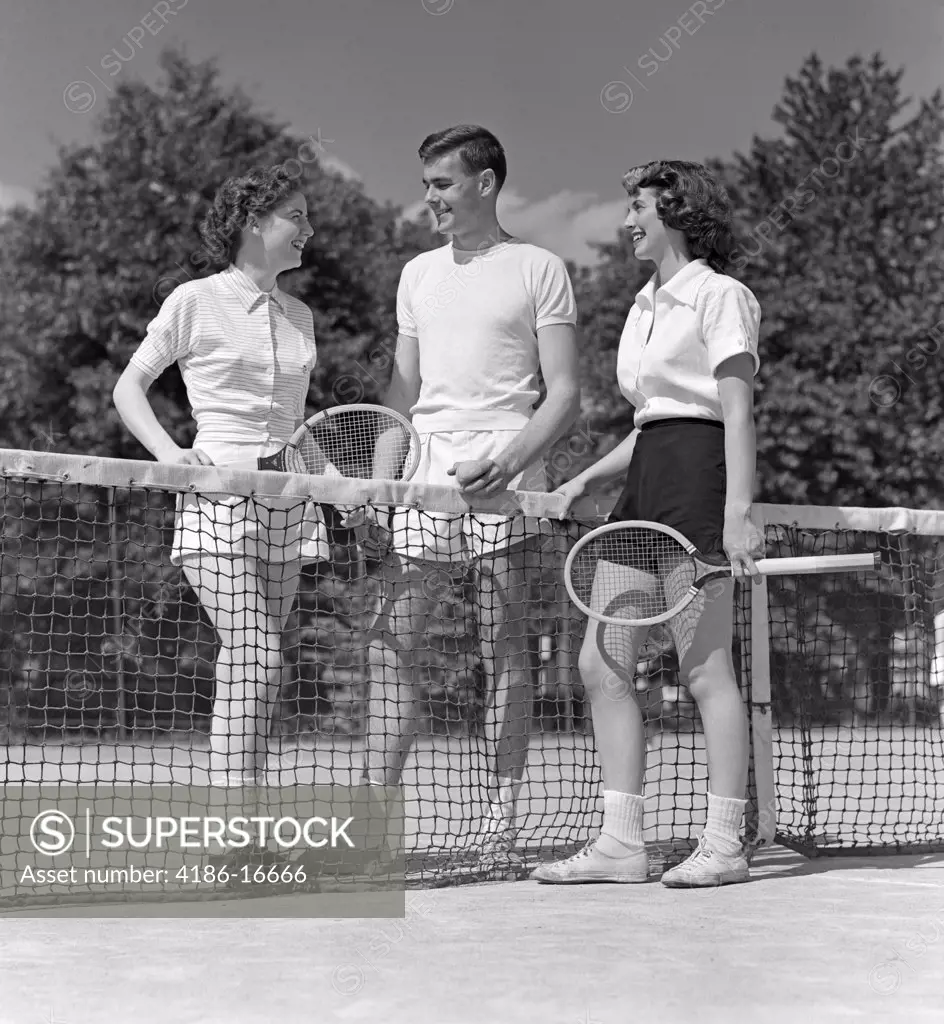 1940S 1950S Two Girls And A Guy Tennis Players Holding Rackets And Tennis Ball Standing Near Net On Court