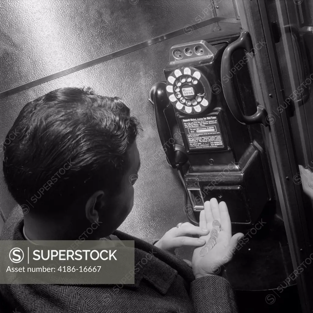 1940S 1950S Man Counting Change In Hand In Public Telephone Booth