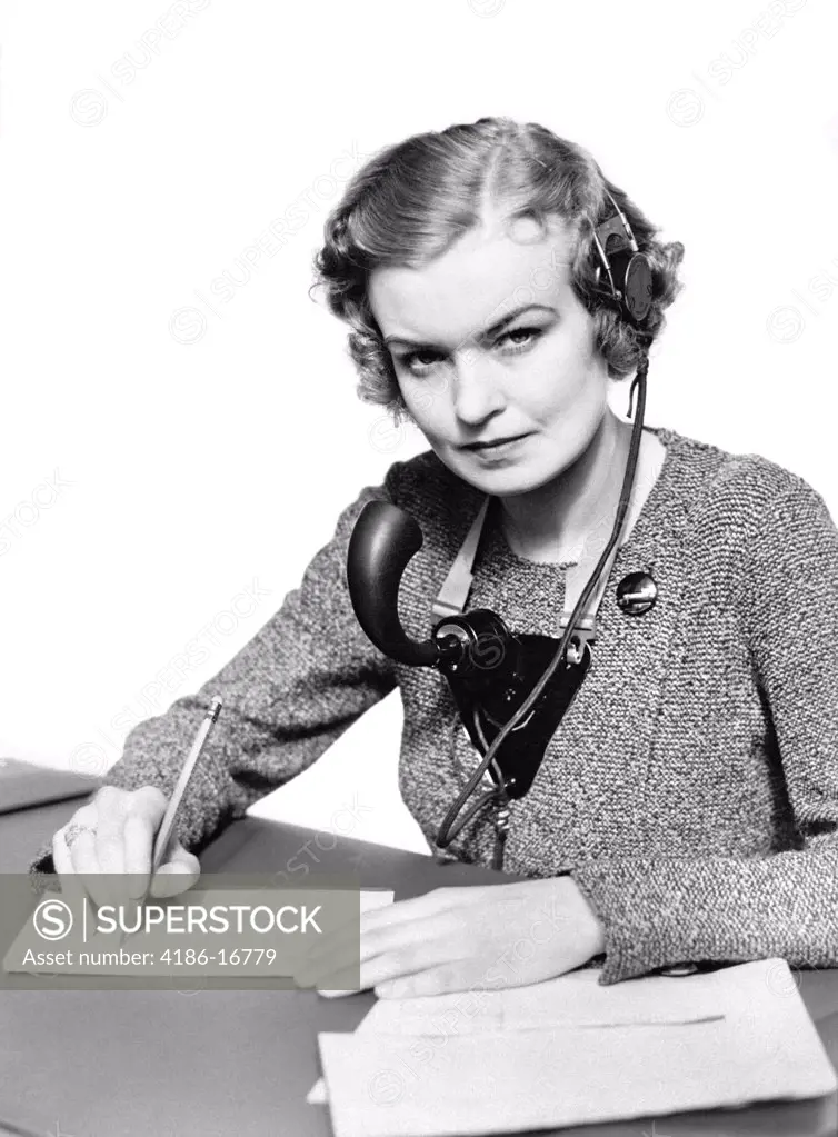 1930S Portrait Business Office Woman Receptionist Wearing Headphones And Speaker Microphone Serious Look Writing On Message Pad