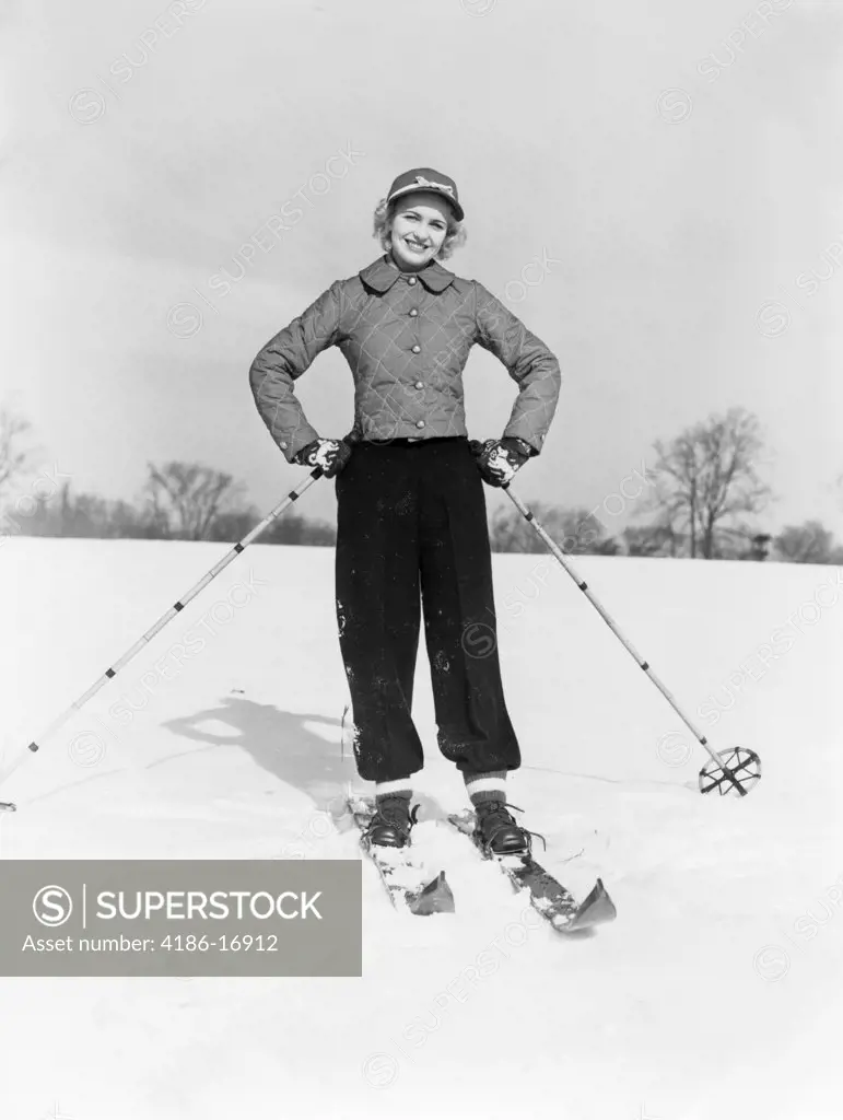 1940S 1950S Smiling Woman On Skis With Cap And Quilted Ski Jacket With Both Hands On Hips