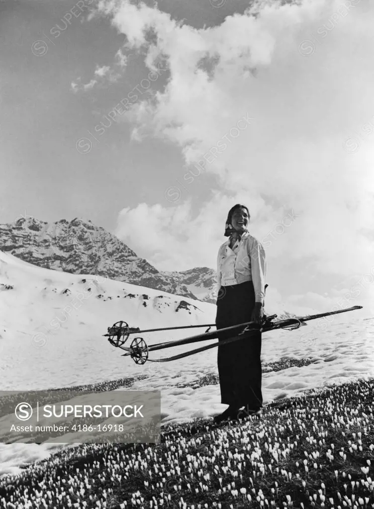 1930S Woman Holding Skis Poles Standing On Crocuses In Snowy Alps Near Davos Switzerland Spring Change Of Seasons